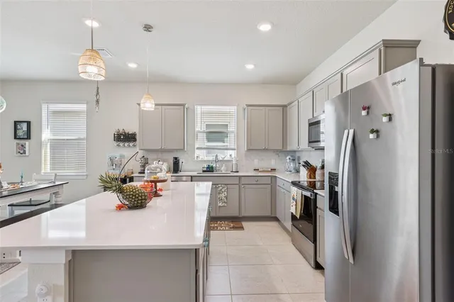 a kitchen with stainless steel appliances a sink a stove a refrigerator cabinets and living room view