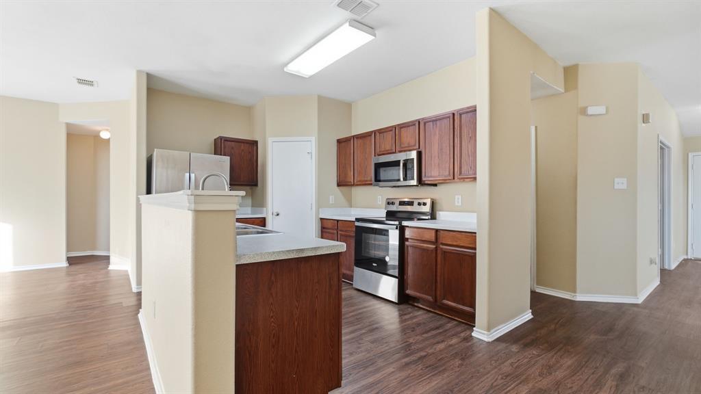 101 Long Prairie Drive Forney, TX 75126 - Photo 10 of 40 a kitchen with kitchen island wooden cabinets a refrigerator stove and wooden floor