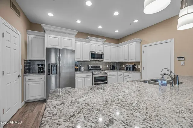 a kitchen with granite countertop a refrigerator and a stove top oven
