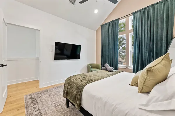 a bedroom with a bed television and a window