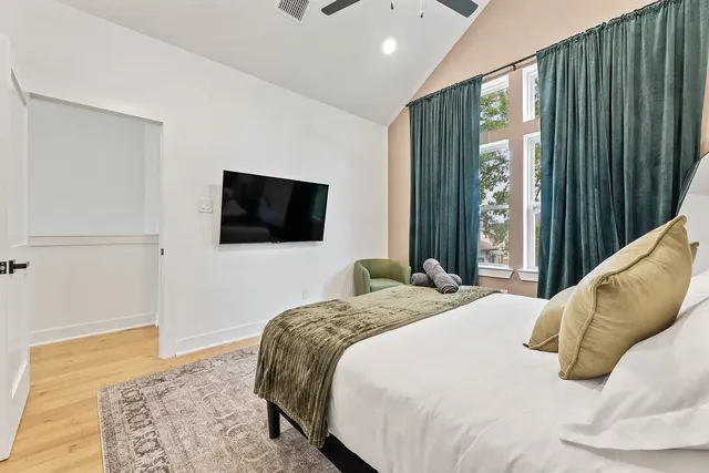 a bedroom with a bed television and a window