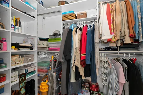 a view of walk in closet with clothes and shoes