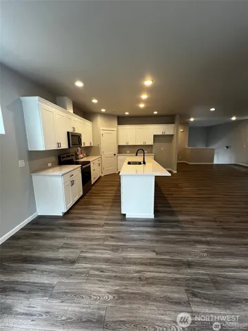 a large white kitchen with kitchen island a sink a stove and a refrigerator