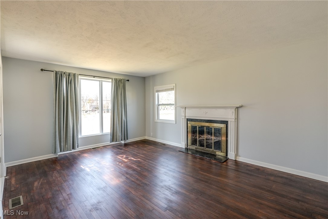 living room featuring Hard wood flooring, a textured ceiling, and a glass covered fireplace