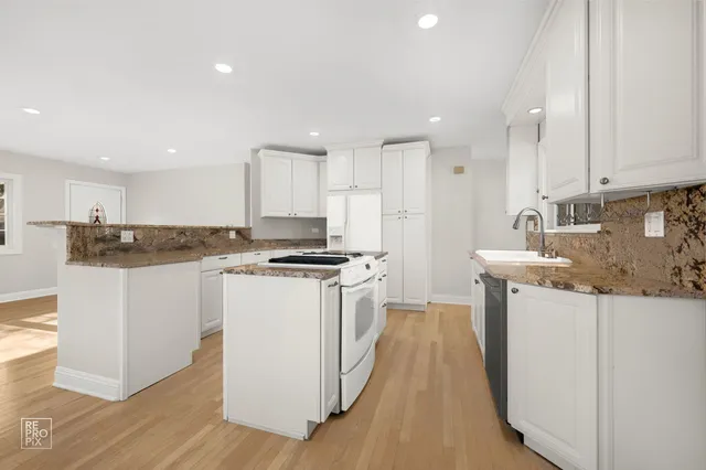 a kitchen with granite countertop white cabinets and white appliances