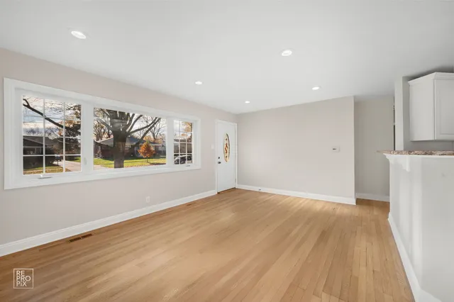 a view of an empty room with a window and wooden floor