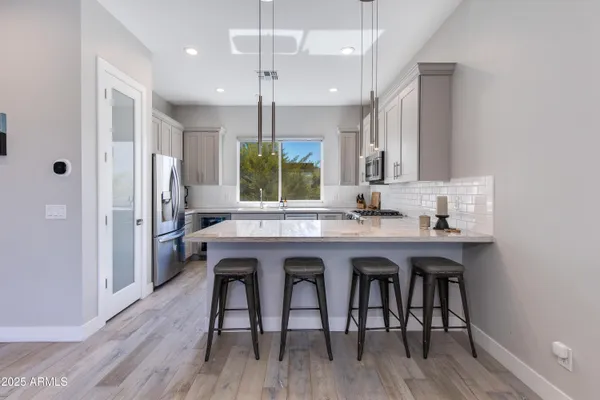 a kitchen with stainless steel appliances granite countertop a table chairs sink refrigerator and microwave