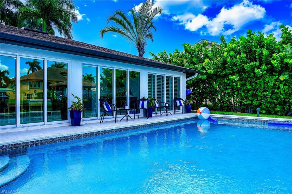 343 Conners Avenue Naples, FL 34108 - Photo 26 of 34 a view of pool with lawn chairs and garden