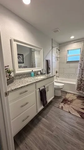 a bathroom with a granite countertop sink mirror vanity and toilet