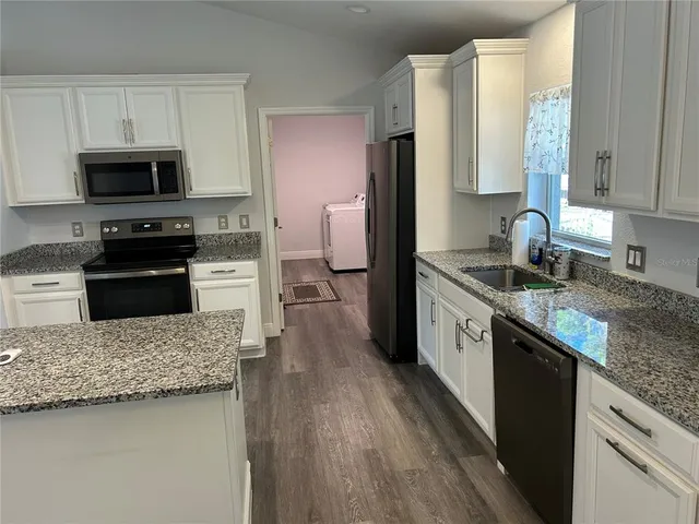 a kitchen with stainless steel appliances granite countertop a sink stove microwave and refrigerator