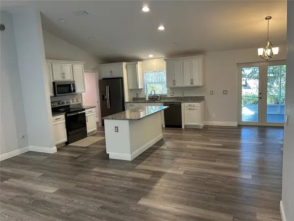 a large kitchen with cabinets wooden floor and stainless steel appliances