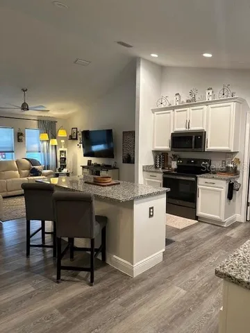 a kitchen with stainless steel appliances granite countertop a stove top oven a sink dishwasher a dining table and chairs with wooden floor