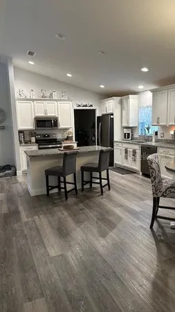 a living room with stainless steel appliances furniture and a kitchen view