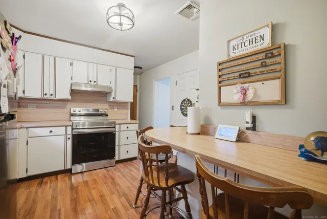 a kitchen with granite countertop a stove a sink dishwasher and a refrigerator with wooden floor