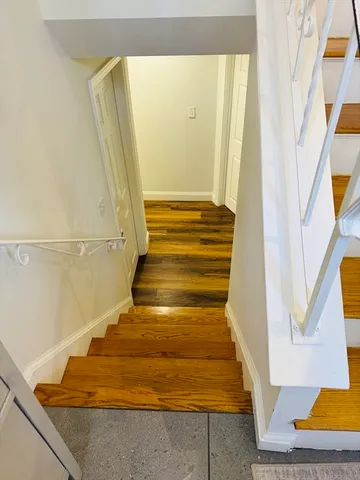 a kitchen with stainless steel appliances granite countertop a refrigerator a stove a sink a dining table and chairs with wooden floor