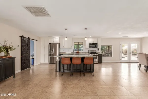 a open kitchen with stainless steel appliances a dining table chairs and granite counter tops