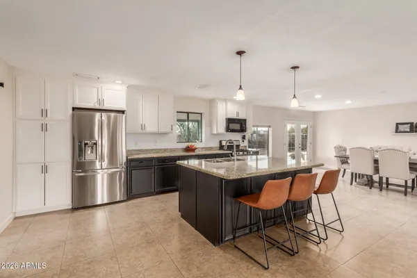 a kitchen with stainless steel appliances granite countertop a sink a stove a refrigerator and island with wooden floor