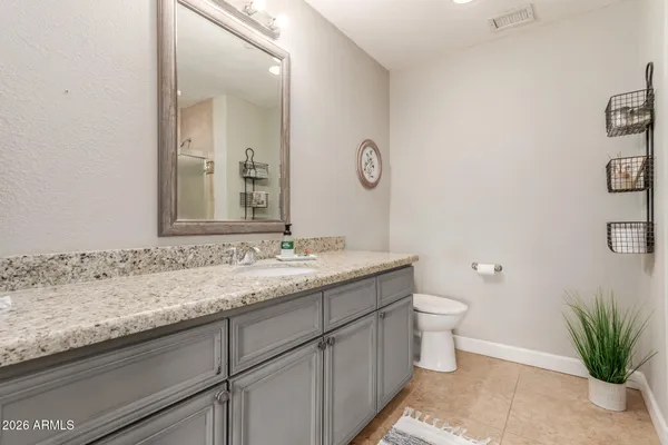 a bathroom with a granite countertop sink a toilet and mirror