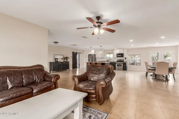 a living room with furniture kitchen view and a chandelier