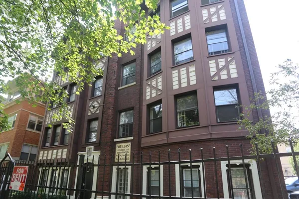 a view of a brick building next to a large tree