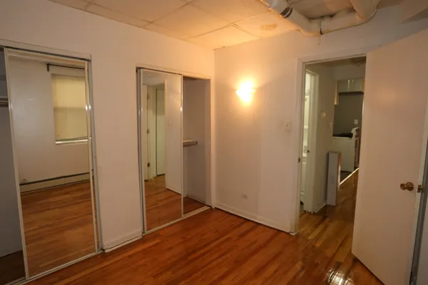 a view of a hallway with wooden floor and a bathroom