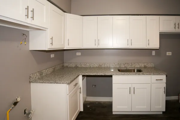a kitchen with granite countertop white cabinets and a sink