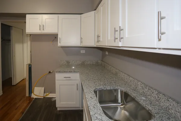 a kitchen with granite countertop white cabinets and stainless steel appliances