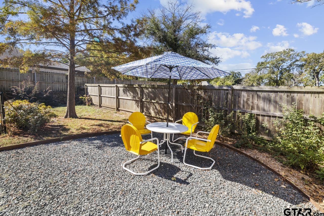 403 East Houston Street Tyler, TX 75701 - Photo 37 of 44 a view of a backyard with table and chairs under an umbrella with wooden fence