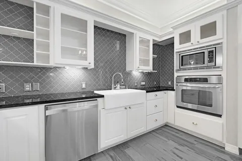 a kitchen with stainless steel appliances granite countertop a stove and white cabinets