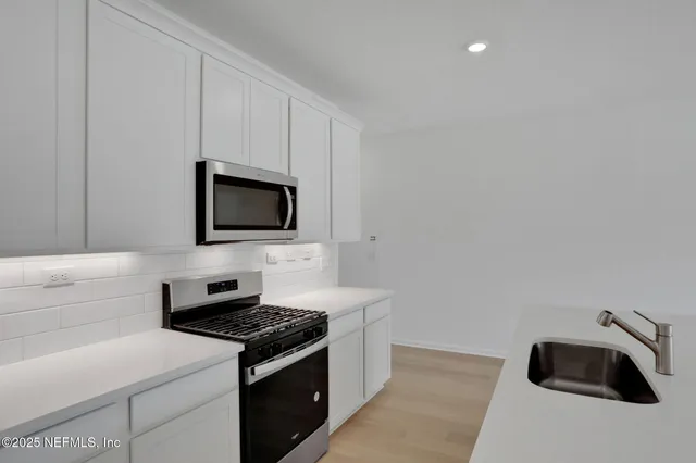 a kitchen with stainless steel appliances white cabinets and a stove top oven