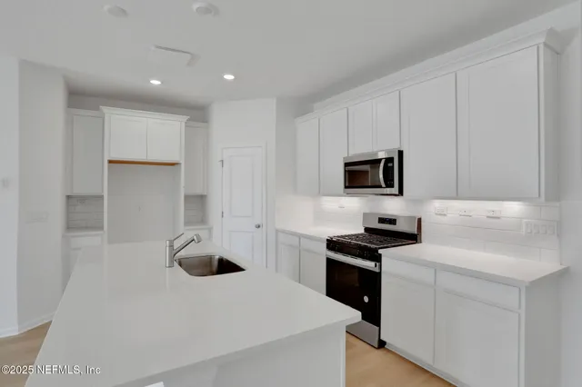 a kitchen with white cabinets and stainless steel appliances