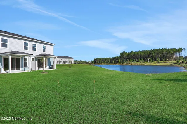 a front view of a house with a garden and lake