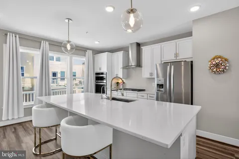 a kitchen with stainless steel appliances granite countertop a table chairs and refrigerator