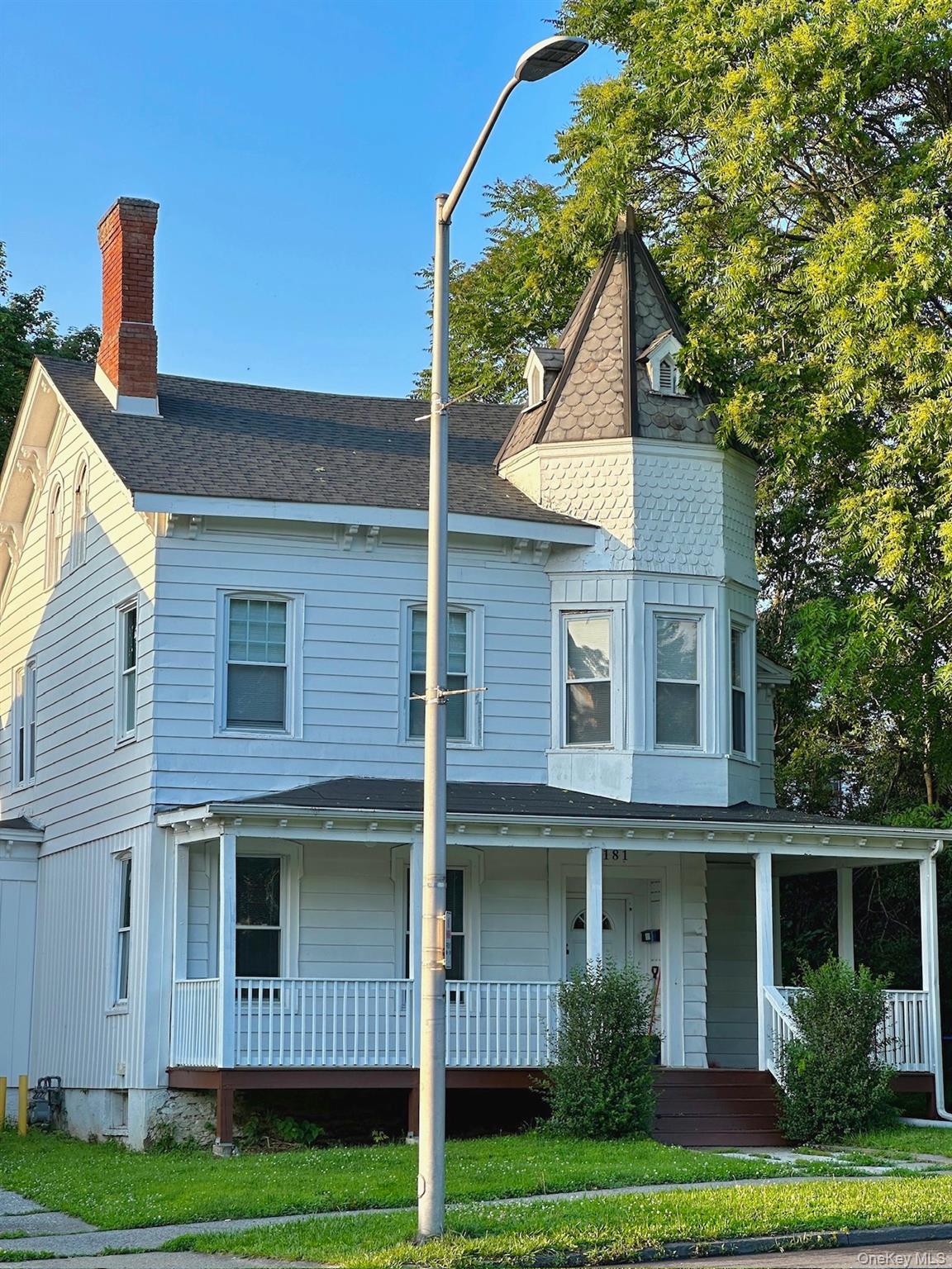 Victorian house with roof with shingles, a porch, and a chimney