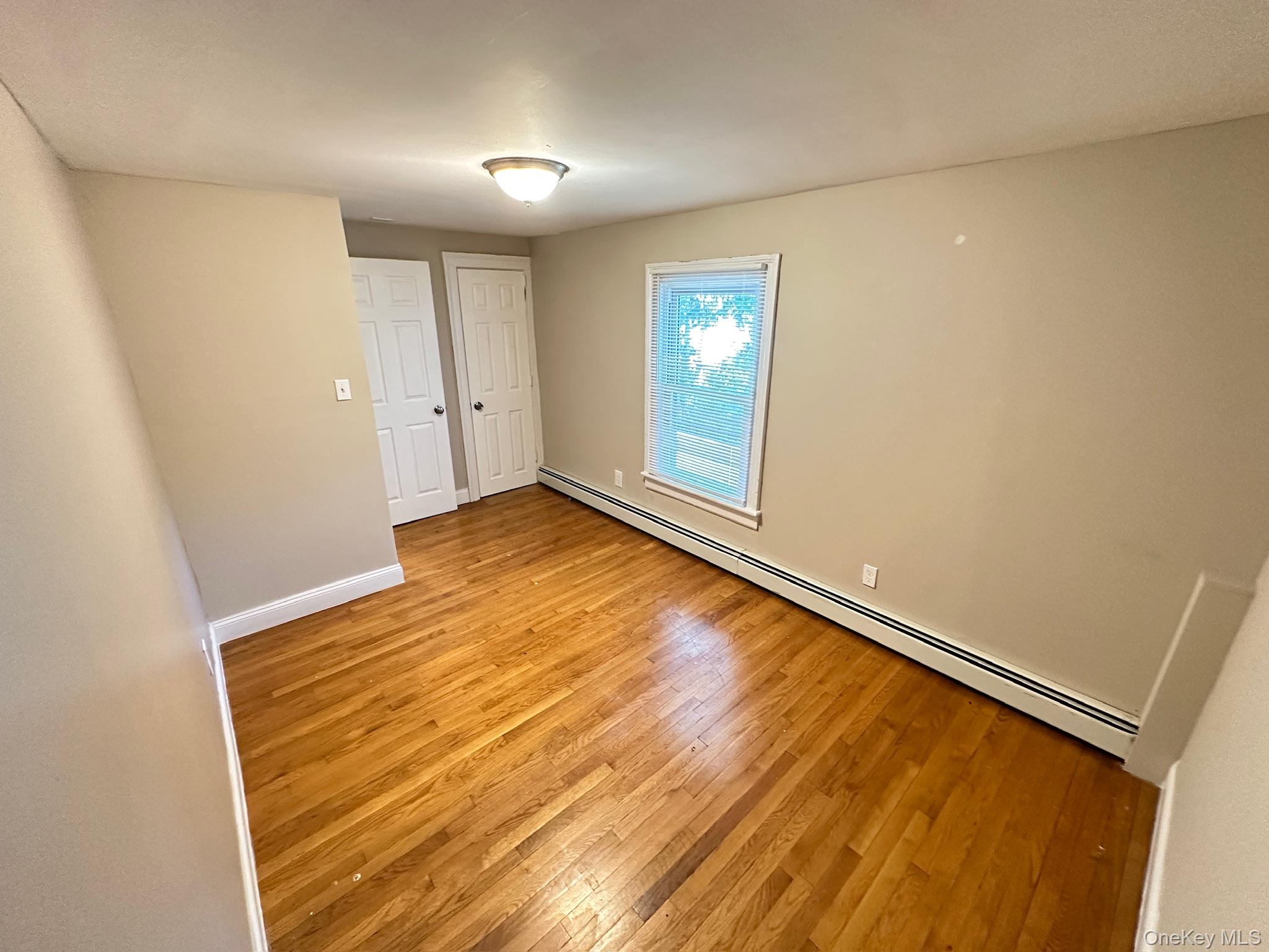 181 Mansion Street, Unit 2 Poughkeepsie, NY 12601 - Photo 15 of 20 Unfurnished bedroom with a baseboard heating unit and light wood-style floors