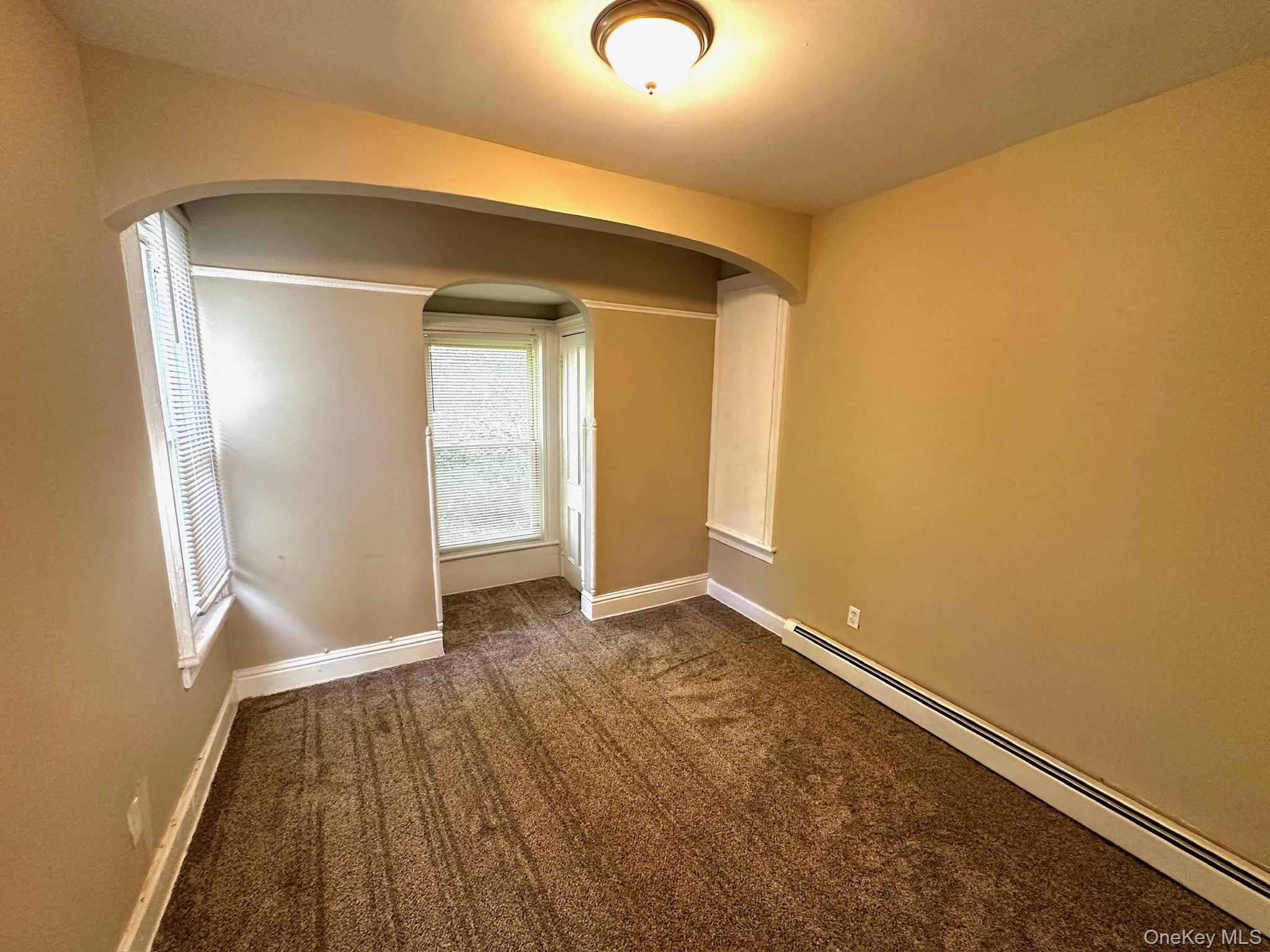 181 Mansion Street, Unit 2 Poughkeepsie, NY 12601 - Photo 18 of 20 Carpeted spare room with a baseboard radiator and arched walkways