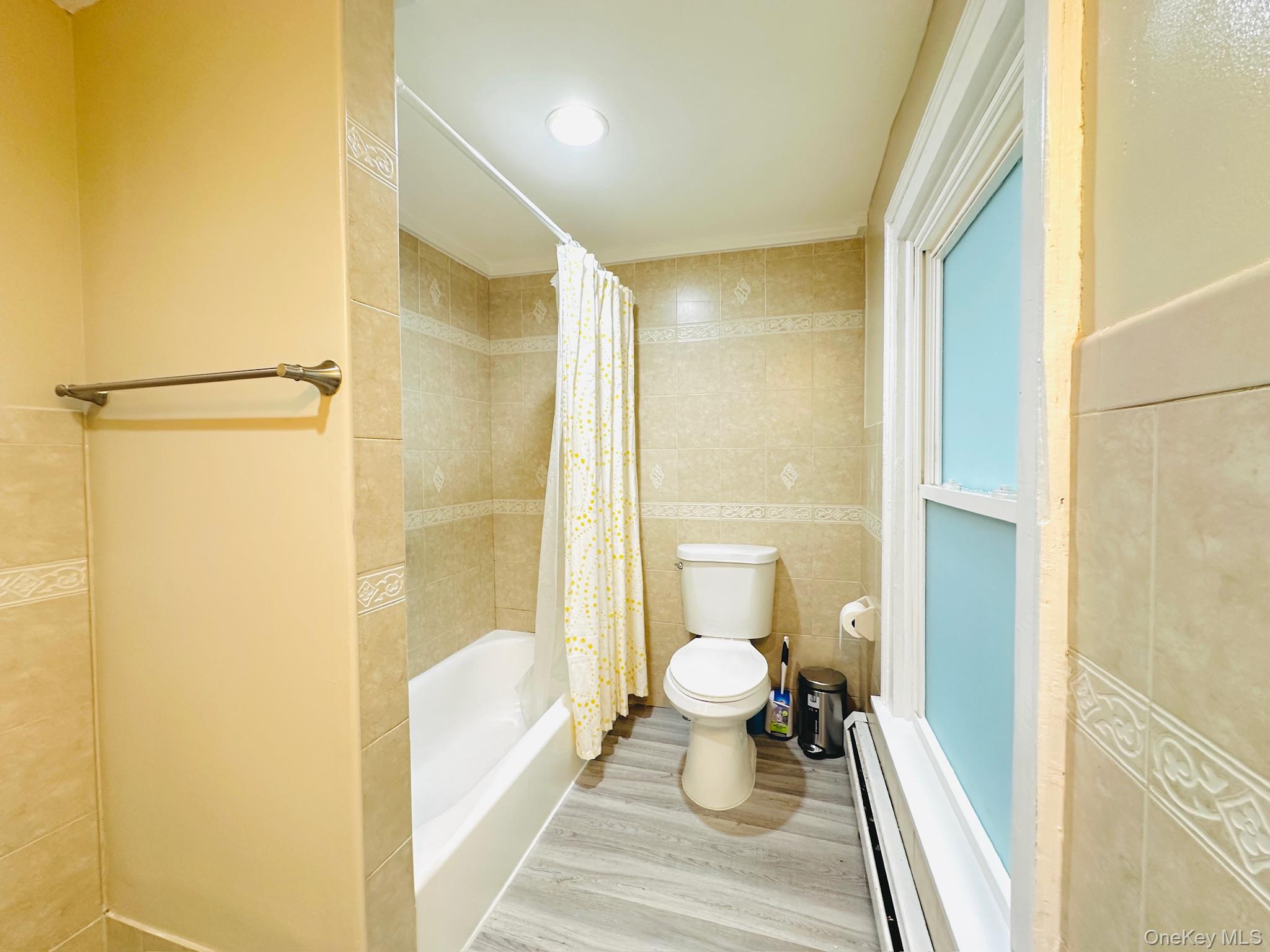 181 Mansion Street, Unit 2 Poughkeepsie, NY 12601 - Photo 8 of 20 Bathroom with tile walls, baseboard heating, shower / tub combo with curtain, and wood finished floors