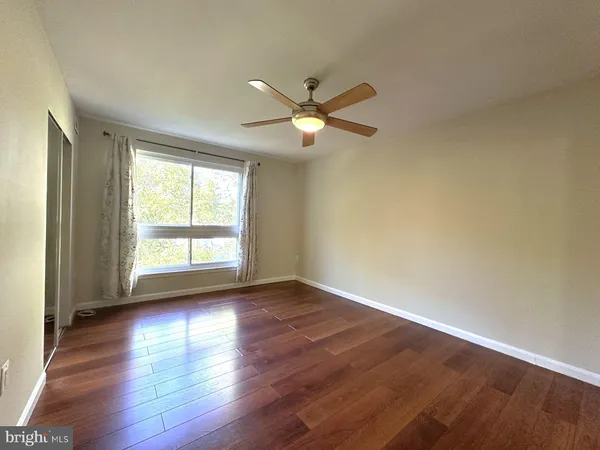 a view of empty room with wooden floor and fan