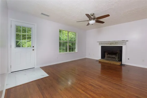 an empty room with wooden floor a ceiling fan and a window