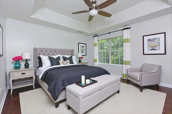 a bed sitting in a bedroom next to a window with a potted plant on a stool