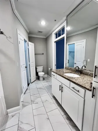 a spacious bathroom with a granite countertop sink a mirror and a toilet