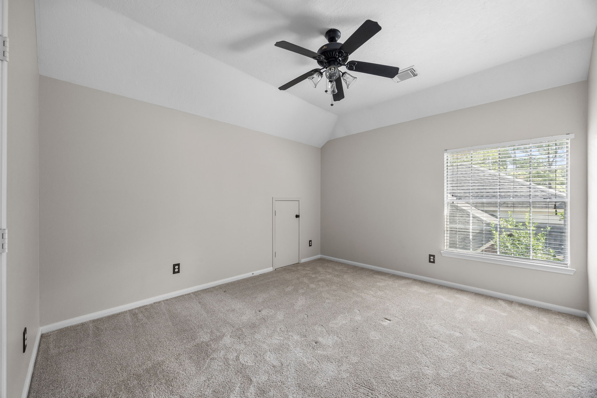 9015 Rhapsody Lane Houston, TX 77040 - Photo 36 of 39 Another secondary bedrooms upstairs, featuring a vaulted ceiling, generous room size, and a large window that brings in plenty of natural light.