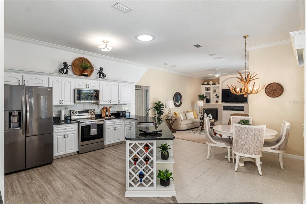 5711 Northwest 25th Loop Ocala, FL 34482 - Photo 21 of 91 a kitchen with stainless steel appliances granite countertop a refrigerator a stove a sink a dining table and chairs with wooden floor