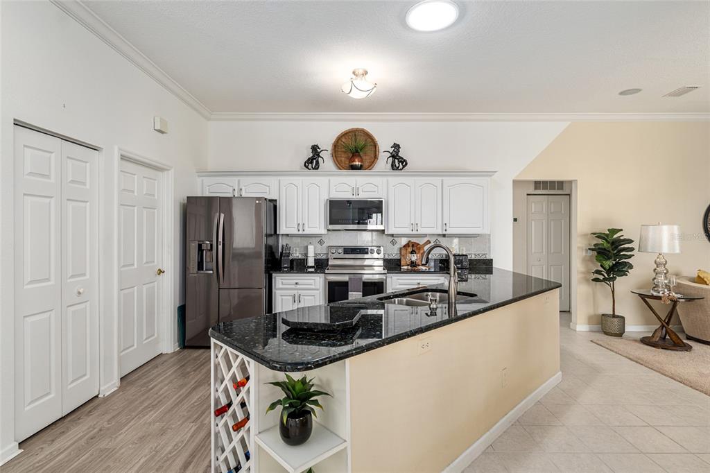 5711 Northwest 25th Loop Ocala, FL 34482 - Photo 32 of 91 a kitchen with stainless steel appliances a refrigerator a stove a sink dishwasher and white cabinets with wooden floor