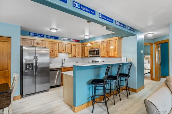 a kitchen with stainless steel appliances kitchen island granite countertop dining table chairs cabinets and a sink
