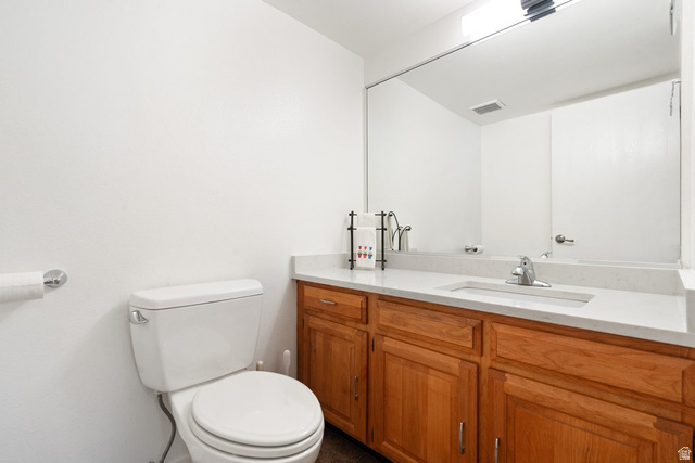 865 South 325 West Orem, UT 84058 - Photo 21 of 38 Bathroom featuring a light wood-finish vanity with a light countertop, an integrated sink with chrome faucet, a large wall-mounted mirror, and a toilet