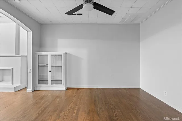 an empty room with wooden floor cabinet and windows