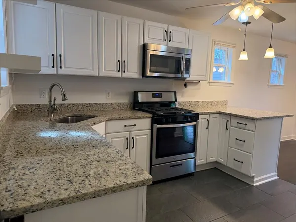 a kitchen with granite countertop a sink a stove and a microwave
