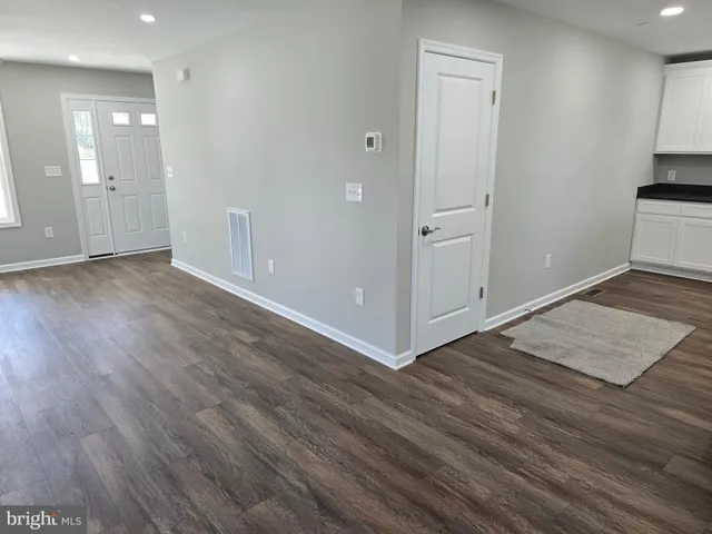 an empty room with wooden floor & cabinet and a sink