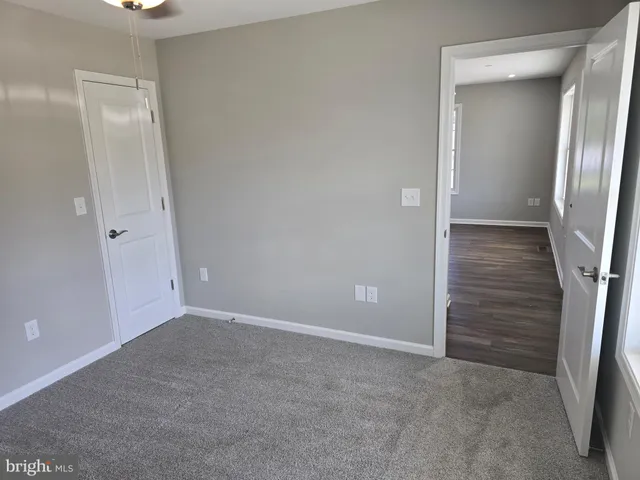 a view of an empty room with closet and mirror